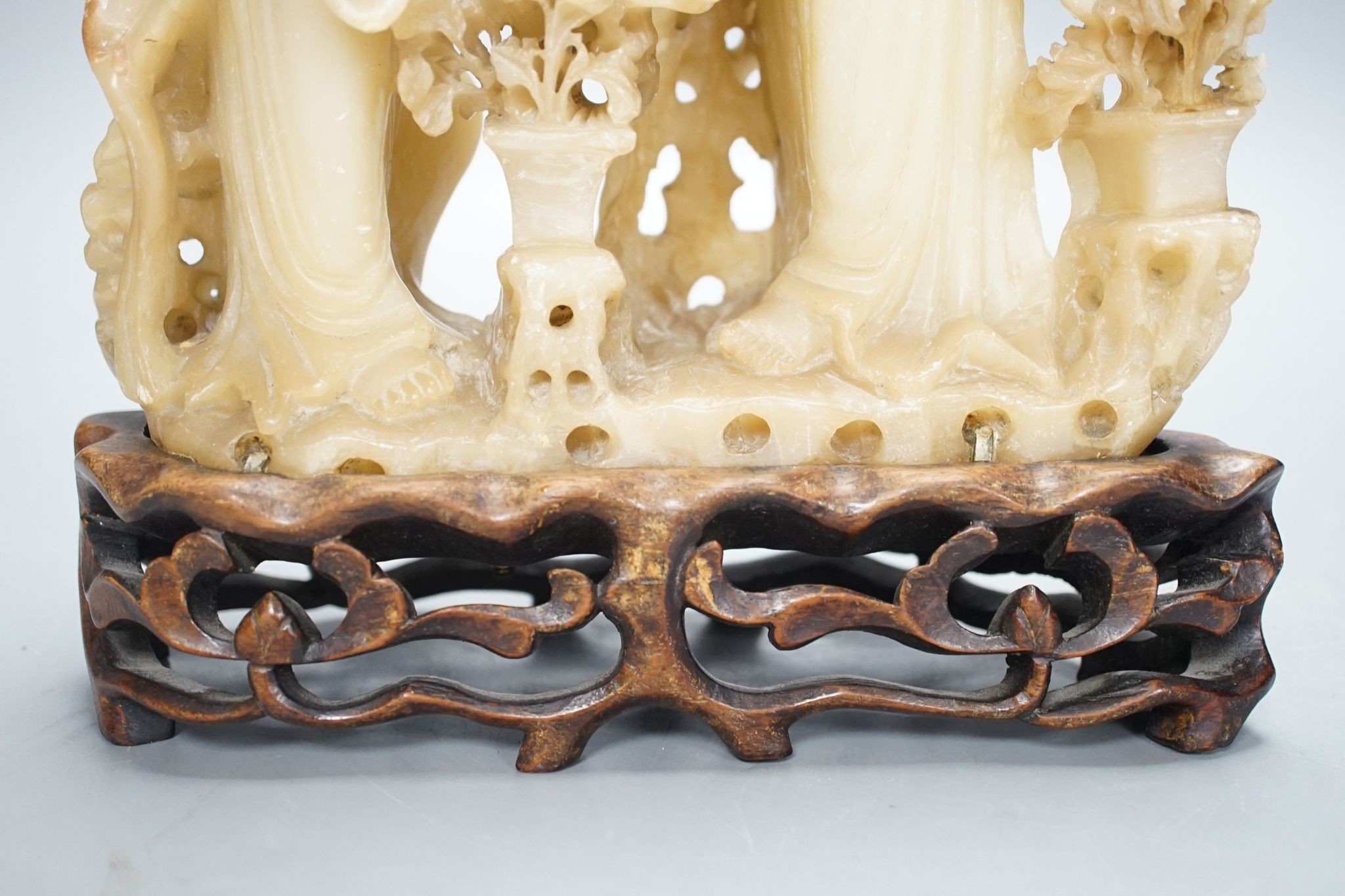 A Chinese soapstone carving of two ladies, wood stand, early 20th century, 36 cms high.